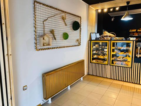 Magazinul Pandipo Gara: perete decorat cu spice și mușchi, radiator auriu și vitrine cu patiserie